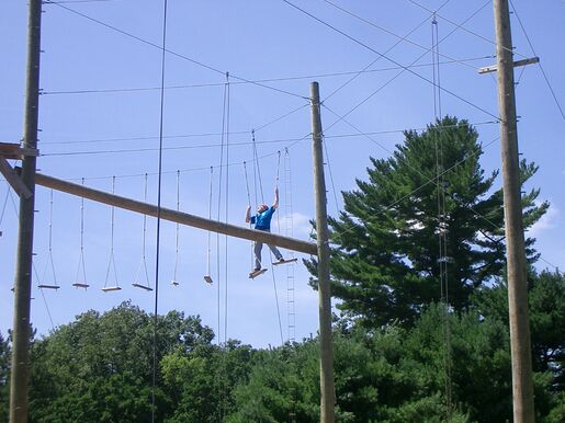 A scout from Troop 106 traversing planks on a high COPE course