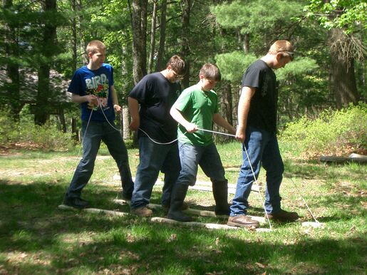 Four scouts walking together on planks as part of a teamwork exercise